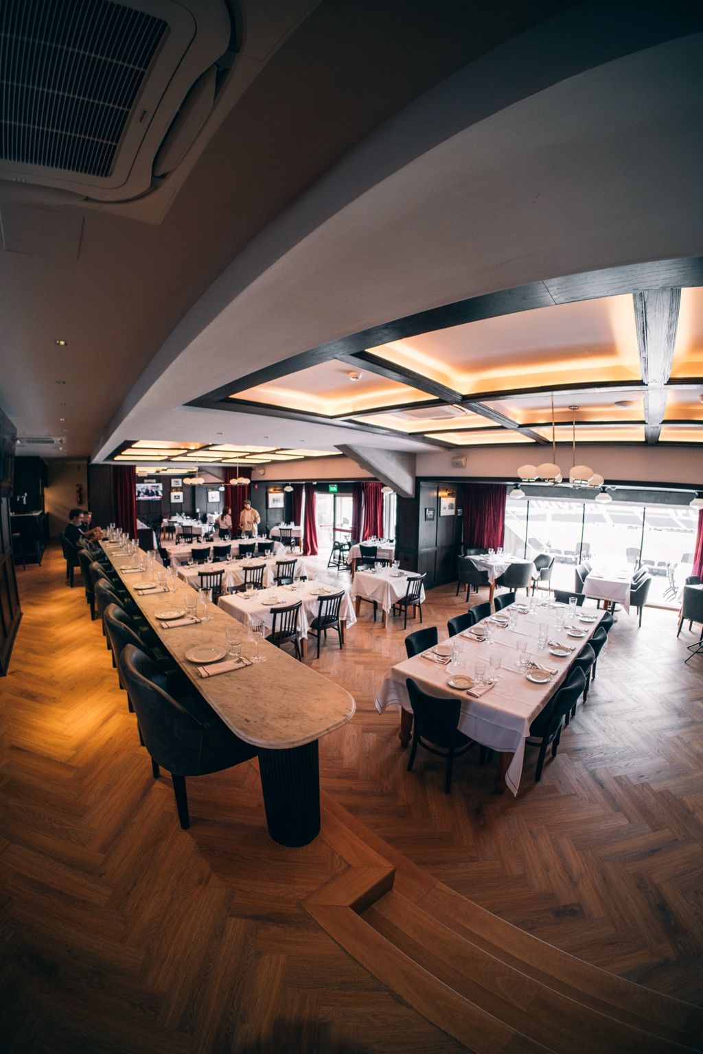 Salón principal de Bodegón 1901 con barra de mármol, pisos de madera y vista al campo