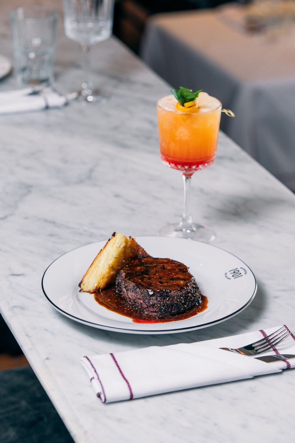Lomo a la pimienta con coctel en barra de mármol
